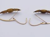 two pairs of gold earrings with leaves on them on a white surface