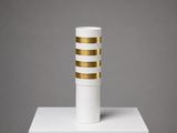 un vase blanc et doré posé sur un socle blanc