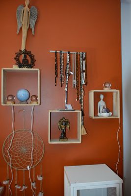 un mur orange sur lequel est posée une étagère remplie de bijoux