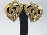 une paire de boucles d'oreilles vintage dorées, présentées sur un support noir