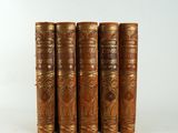a set of five antique leather books on a white background