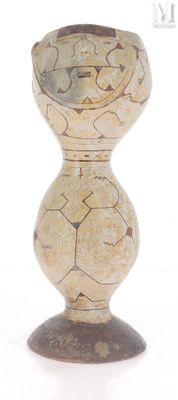 un petit vase avec un motif sur une surface blanche