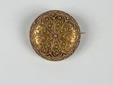 gros plan d'une broche en or sur une surface blanche