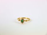 gros plan d'une bague en or avec une pierre verte