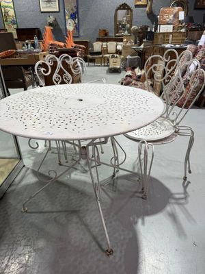 une table et des chaises blanches dans une pièce où il y a beaucoup de meubles