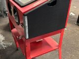 une petite armoire rouge avec un plateau en verre, posée sur un pied