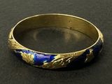 un gros plan d'une bague dorée et bleue posée sur une surface noire
