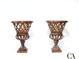 une paire de vases en bois sculpté posés sur des socles, sur fond blanc