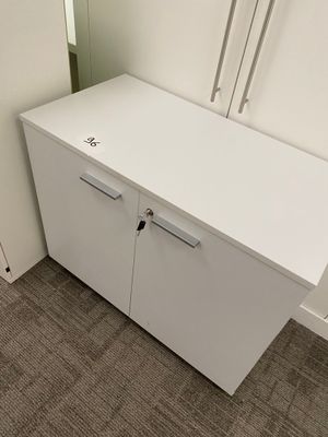 a white cabinet in the corner of a room with a mirror
