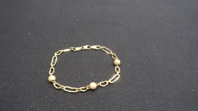 a close up of a gold chain bracelet on a black surface