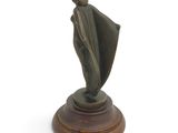 statue of a woman holding a shawl on a wooden base