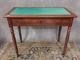 une vieille table en bois avec un plateau en verre vert, posée sur un tapis