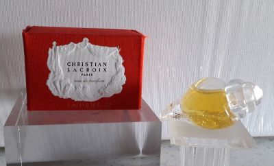 une petite cloche en verre posée sur une table, à côté d'un flacon de parfum