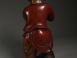 an old wooden statue of a man sitting on top of a rock