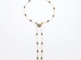un collier de perles blanches orné d'un pompon en perles noires et blanches