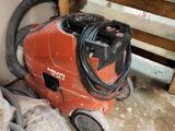 a red vacuum cleaner sitting on the floor next to a pile of trash