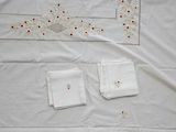 a white table cloth with red and yellow flowers on it