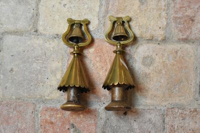 paire de cloches en laiton sur un mur de briques avec un mur de briques en arrière-plan