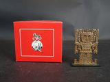 une image représentant une petite figurine en or posée à côté d'une boîte rouge