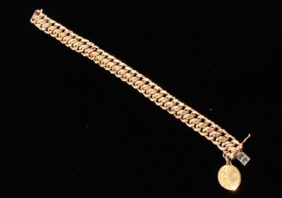 a close up of a gold bracelet with a coin on it