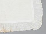 a white cloth with a ruffled edge on a gray surface