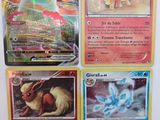 Quatre cartes Pokémon sont posées sur une table avec un fond blanc.