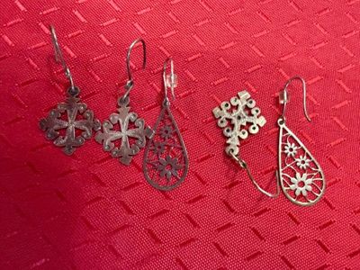 trois paires de boucles d'oreilles posées sur un fond rouge