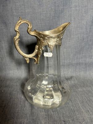 un pichet ancien en verre avec une anse dorée sur fond gris