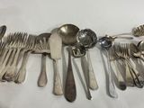 a lot of silverware on a white table cloth