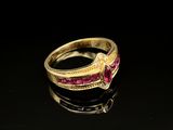 un gros plan d'une bague en or sertie de pierres roses sur un fond noir