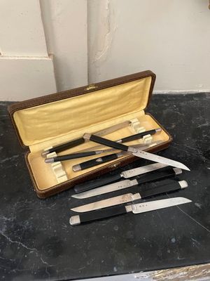 trois couteaux dans un étui posé sur une table