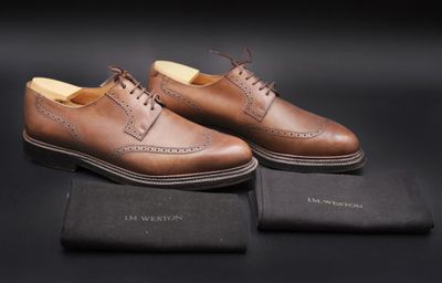 une paire de chaussures en cuir marron pour homme posée sur une surface noire