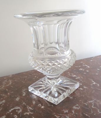 un vase en verre posé sur une table, elle-même posée sur une autre table
