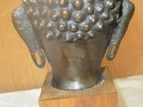 a statue of a buddha head on a wooden stand