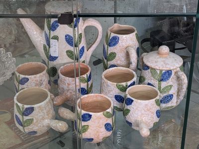 a glass display case with a variety of pottery items