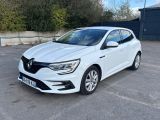une voiture blanche garée sur un parking près d'une clôture