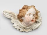 une tête d'ange blanche accrochée au mur, à côté d'un mur blanc