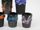 four black cups with different colored designs on them sitting next to each other