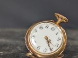 une petite montre de poche en or posée sur une surface en marbre