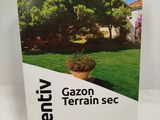 un gros plan sur une boîte de « Gazon Terrarin Sec » posée sur une table