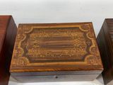 three wooden boxes with decorative designs on them sitting on a white surface