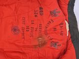 a red jacket with black writing on it sitting on a bed
