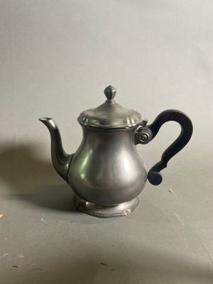une théière en argent avec une anse noire posée sur une table