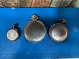 three silver pocket watches sitting on top of a blue tray