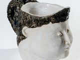 un vase blanc surmonté d'une tête noire