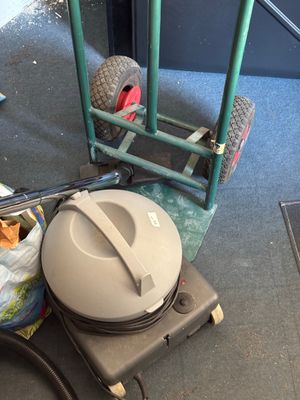 une photo d'un aspirateur posé par terre à côté d'un chariot