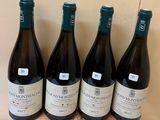 four bottles of wine are lined up on a wooden tray