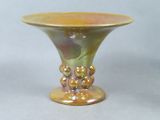 a yellow vase with pearls on it sitting on a table