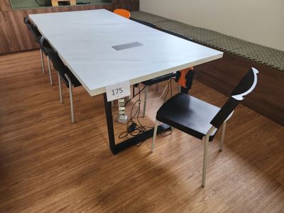 une table blanche avec des chaises noires et un ordinateur portable posé dessus
