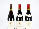 three bottles of wine are lined up on a white surface